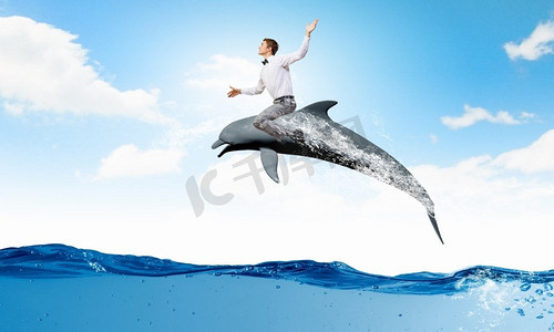 年轻开朗的人骑着海豚跳水.