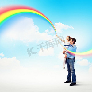 父亲抱着女儿和彩虹。幸福的父亲牵着女儿的手形象和彩虹