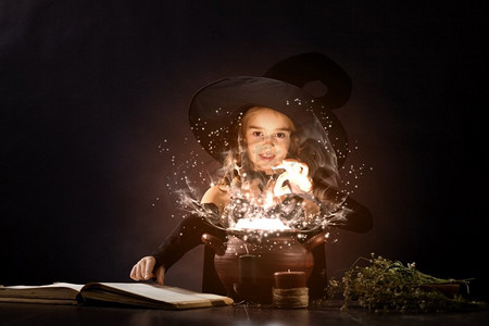 万圣节女巫可爱摄影照片_万圣节女巫。小万圣节女巫在锅上读魔术