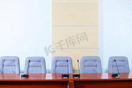 会议礼堂摄影照片_配有麦克风的会议厅。在开会前，麦克风放在空椅子前。