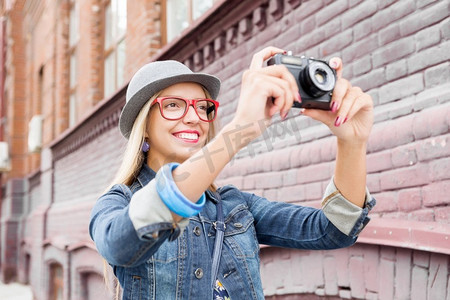 在新城市观光。年轻的女旅行者走在街上，用旧相机拍照
