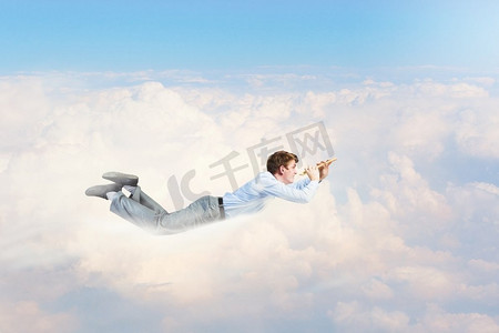 免费建党节摄影照片_休息时间到了。年轻的商人在天空中飞翔，演奏着长笛