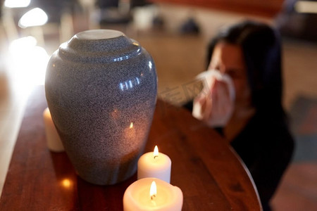 火葬,人和哀悼概念 — 带着抹布和骨灰盒的女人在教堂的葬礼上哭泣.