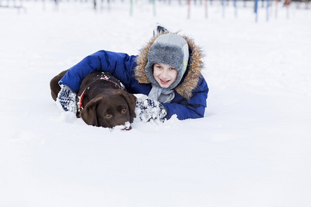 冬季户外男孩摄影照片_学龄儿童与狗在冬季公园。我和我最好的朋友