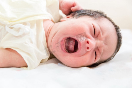 哭的宝贝摄影照片_新生婴儿在床上哭