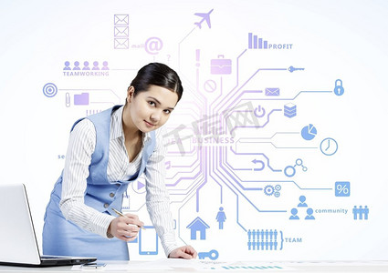 在餐桌旁工作的女人。坐在办公桌前的年轻女商人，背景是笔记本电脑和云计算概念