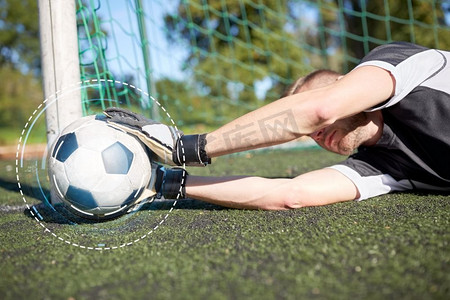 体育和人-足球运动员或守门员躺在足球场上的足球目标的球。守门员与球在足球目标在领域