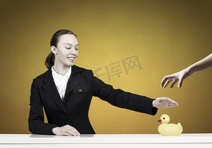 女人与鸭子玩具。年轻的女商人和黄色橡胶鸭玩具在桌子上
