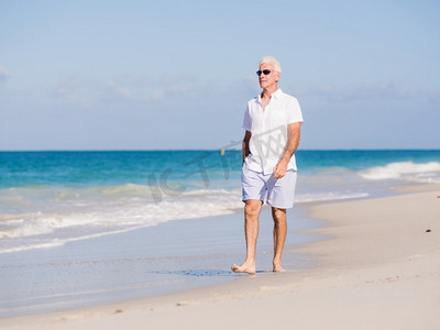 在阳光明媚的日子里，一个穿着白色衣服的男人在海滩上。海滩上美丽的一天