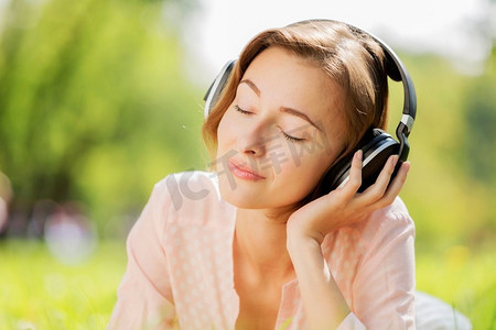 公园里一位年轻漂亮的女士在听音乐。公园里阳光明媚的周末