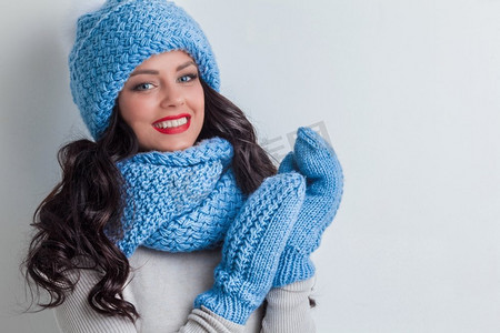 戴着蓝色冬帽、围巾和手套的微笑女子