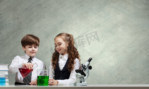 实验课摄影照片_在化学课上。两个可爱的孩子在化学课上做实验