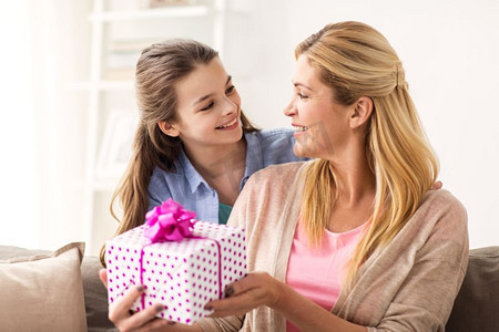 人物、节日和家庭观念--快乐的女孩在家里给妈妈送生日礼物。女孩在家给妈妈送生日礼物