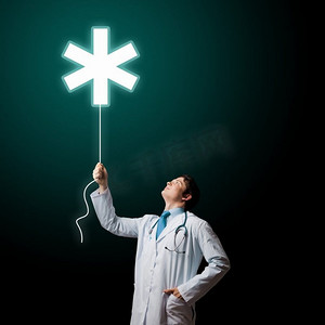 救护车标志摄影照片_男医生。年轻男医生手持带有医学标志的气球