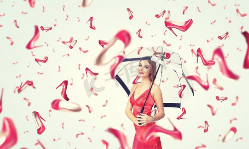 穿着红色鞋的女孩摄影照片_外面正下着雨点。一位打着伞、穿着落地鞋的漂亮年轻女子