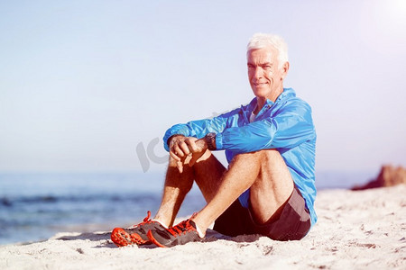 一分钟摄影照片_穿着运动服的男人坐在海滩上。穿着运动服的男人独自坐在海滩上休息一分钟