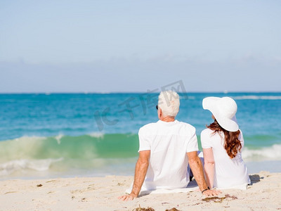 夫妇坐在沙滩上。只有我们和大海
