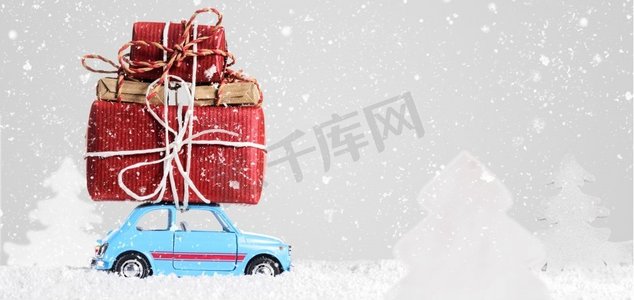 带有圣诞礼物的复古玩具车。蓝色复古玩具车在灰色背景上送圣诞或新年礼物