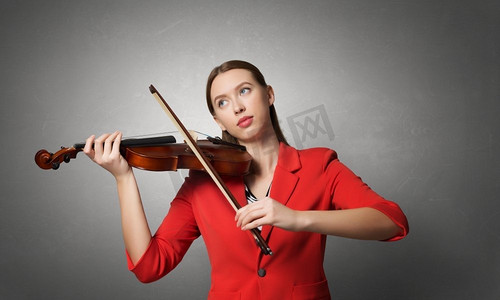 会红色摄影照片_漂亮女人会拉小提琴。穿着红色夹克的年轻漂亮女子在拉小提琴