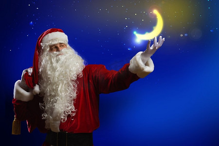 装饰月亮摄影照片_圣诞老人圣诞老人拿着闪闪发光的月亮在手掌