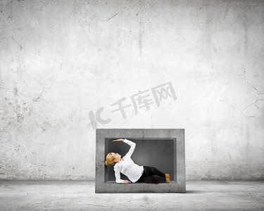 有限摄影照片_有限的和有限的。一名年轻女子被困在墙上的石块中