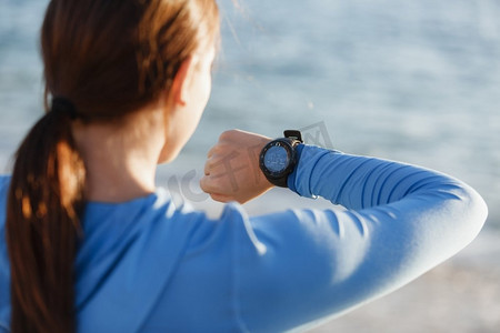 跑步者妇女与心脏率监视器跑在海滩上。有在海滩上跑的心率监视器的年轻赛跑者妇女