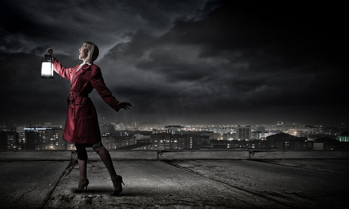 身穿红色斗篷,提着灯笼的年轻金发女子迷失在黑暗中.