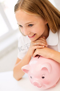 人，储蓄和理财的概念-快乐的女孩在家里存钱罐。家里存钱罐的快乐女孩