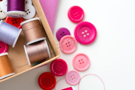 针线活、手工艺、缝纫和剪裁概念--桌子上有线轴和缝纫纽扣的盒子