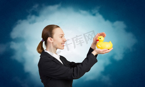 年轻女商人与黄色橡胶鸭玩具。女人和鸭子