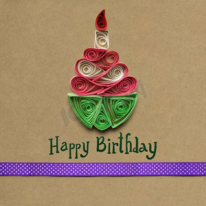 创意概念图，棕色背景用纸做成的羽毛笔生日蛋糕。