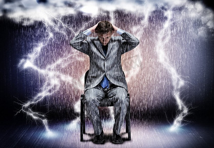 坐在椅子摄影照片_商业上的挑战。陷入困境的商人坐在雨中的概念形象