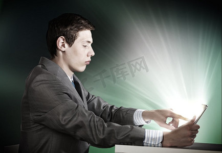 年轻用户摄影照片_使用平板电脑的男子。情绪激动的年轻商人看着平板电脑