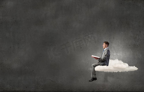 男人在孤独中阅读。年轻的商人坐在云上看书