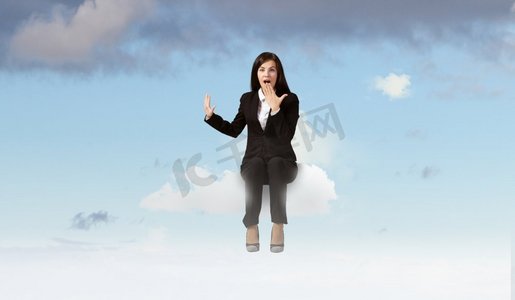 大吃一惊的女商人。年轻情绪化的女商人坐在城市上空的云端