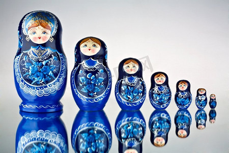 一套七个蓝色的俄罗斯套娃在镜面上。
