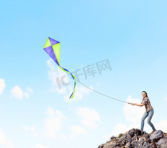 拿着风筝的女人。年轻漂亮的女人站在岩石上，放着五颜六色的风筝