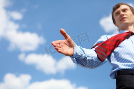 一位穿着蓝色衬衫，打着红色领带的年轻商人伸出手握手