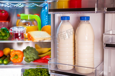 打开冰箱装满食物。关注冰箱里的牛奶瓶