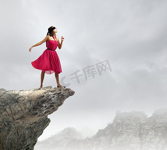蒙着眼睛的女人。站在岩石边上的一位红衣女子