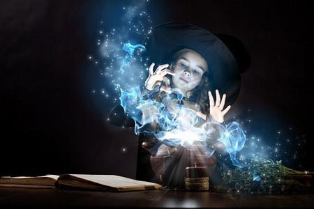 万圣节看书小孩摄影照片_万圣节女巫。小万圣节女巫在锅上读魔术