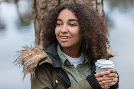美丽幸福的混血黑人少女少女微笑的年轻女子在外面喝着外卖咖啡