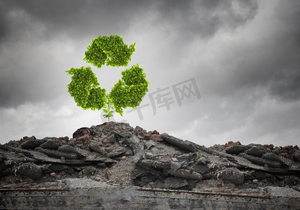 绿色植物图标摄影照片_循环利用的概念。废墟上生长着循环绿色标志的概念形象