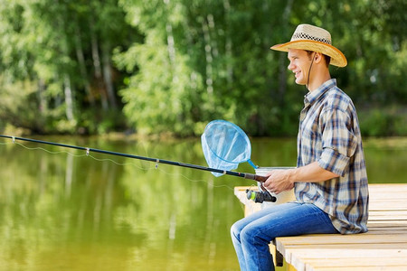 轴流式压缩机摄影照片_夏季钓鱼年轻人在帽子坐在桥和钓鱼