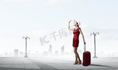 穿红衣服的女人。年轻女子穿着红色连衣裙，背着红色行李箱，用手做着手势