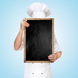 餐厅厨师躲在一块空白的黑板后面，拿着一份商务午餐菜单，上面写着价格。