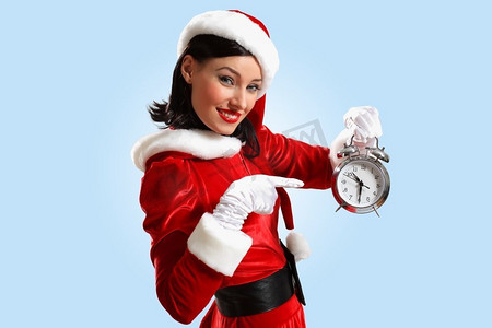 戴着圣诞帽的圣诞女孩。戴着圣诞老人帽子拿着闹钟的兴奋女孩。图解