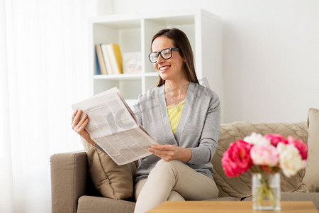 大众传媒和人概念-在家读报纸的愉快的妇女。快乐的女人在家里读报纸