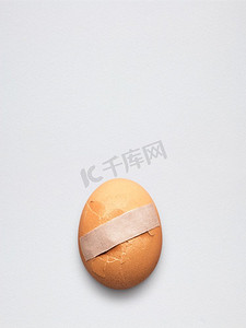 碎鸡蛋摄影照片_创意医药保健理念，将膏药贴在碎鸡蛋上。