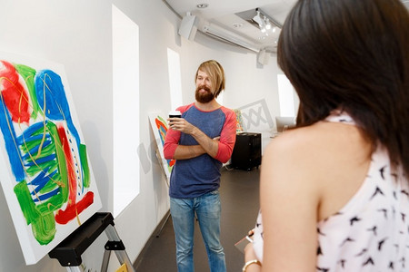 年轻人站在画廊里凝视着艺术品。站在画廊里凝视抽象艺术品的年轻人